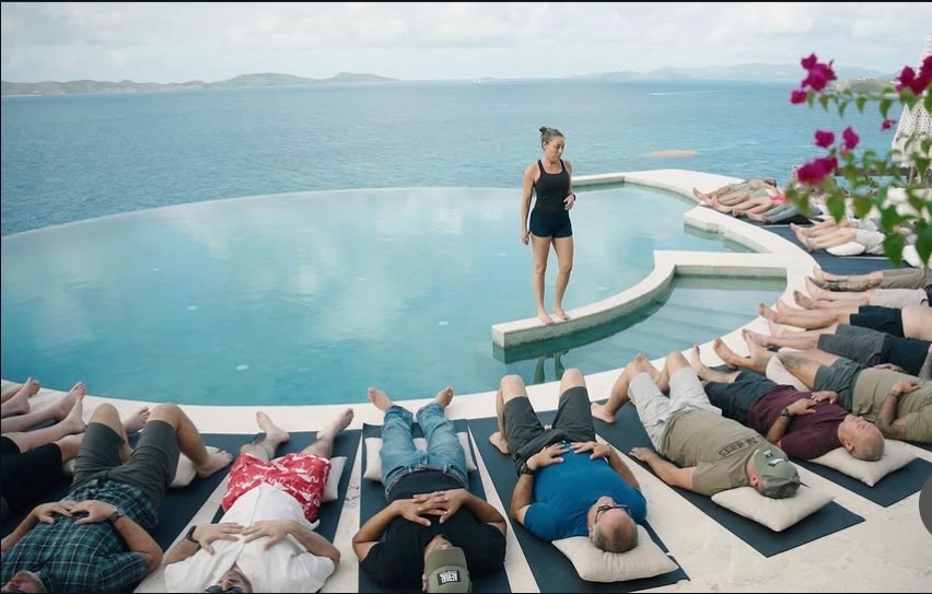 Leah MacClellan leading breathwork by an infinity pool overlooking the ocean